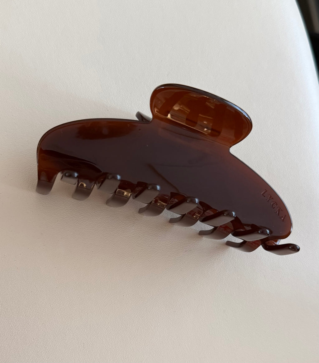 Brown hair clip with “Lycka” engraving on a white background
