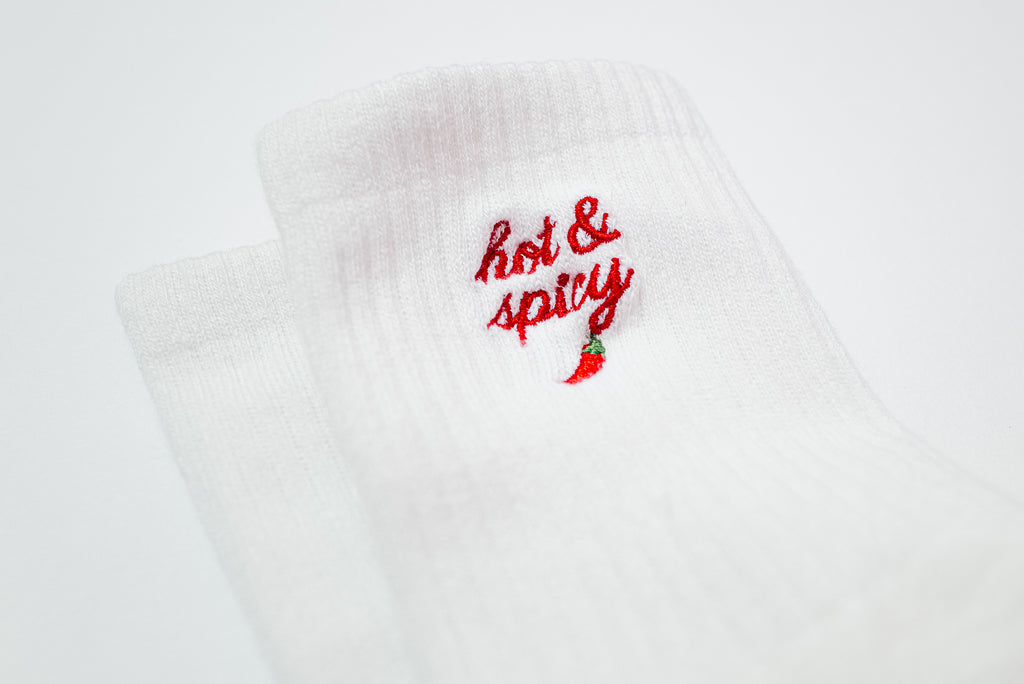 White sock with 'hot & spicy' text and chili pepper embroidery on a white background