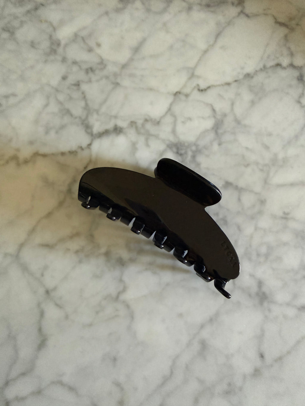 Black hair clip on a marble surface