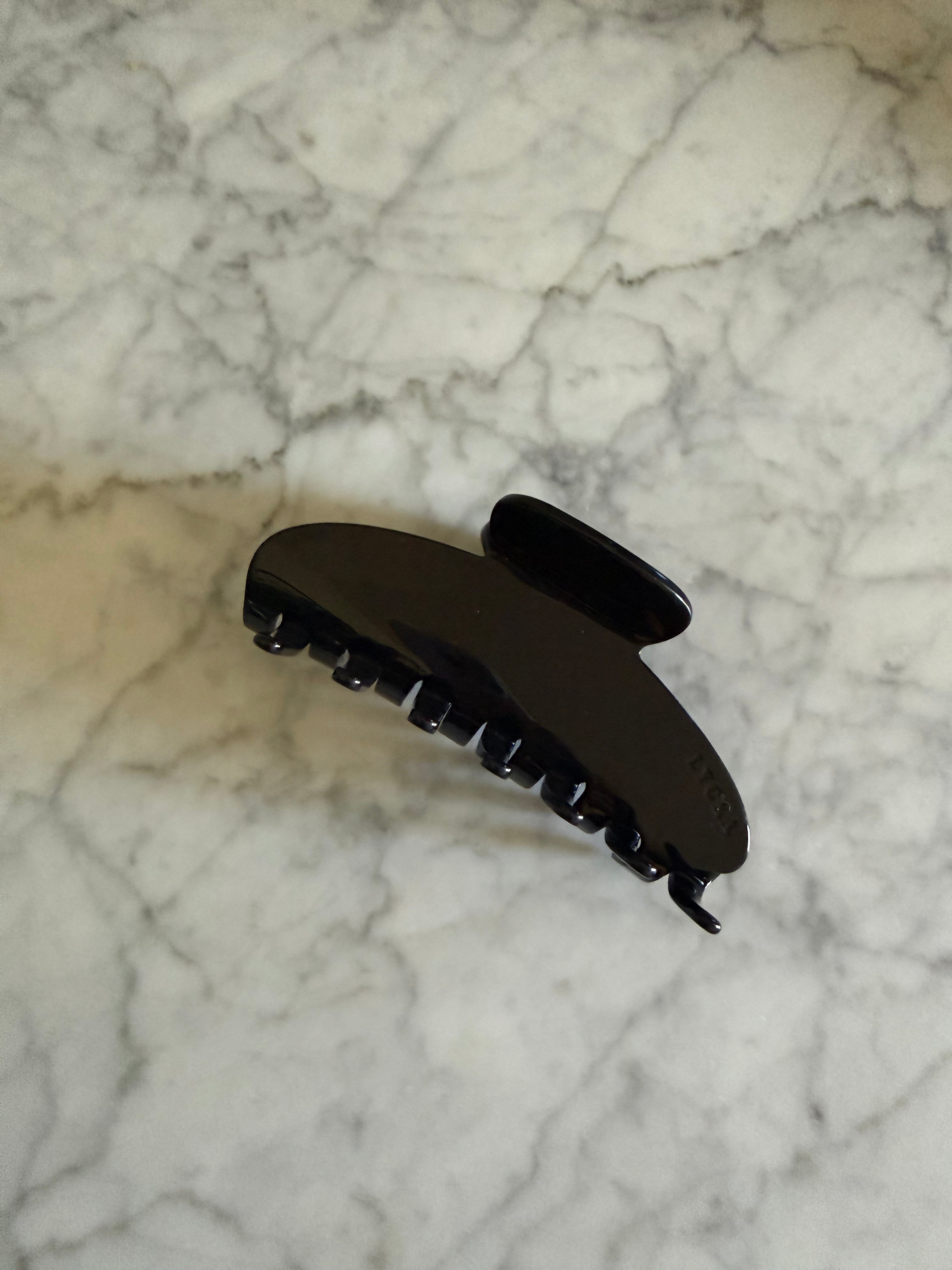 Black hair clip on a marble surface