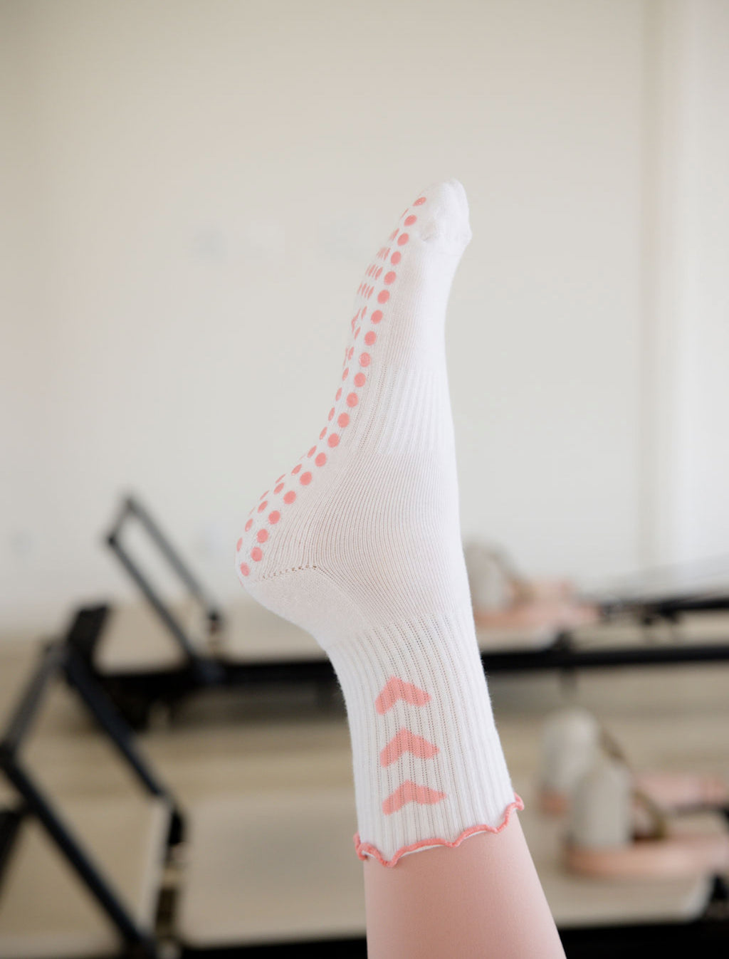 White sock with pink heart accents on a blurred indoor background