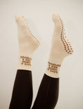 Beige socks with text "save a horse ride a reformer" worn by a person on a plain background