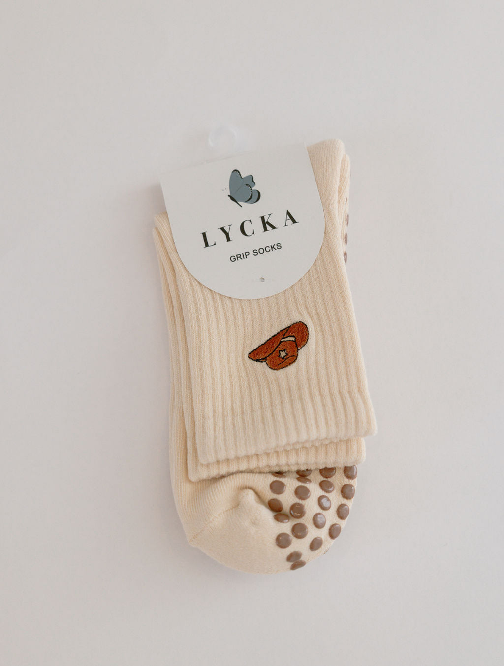 Beige sock with brown cowboy had embroidery and brown grip dots on a white background, featuring Lycka branding