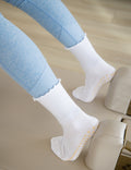 White socks with yellow grips worn by a person using a reformer machine.