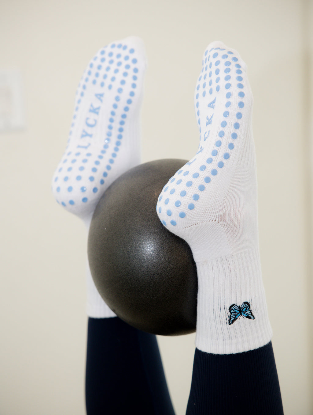 White socks with blue dots and a butterfly design on a neutral background