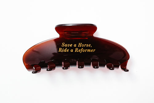 Brown hair clip with 'Save a Horse, Ride a Reformer' text on a white background