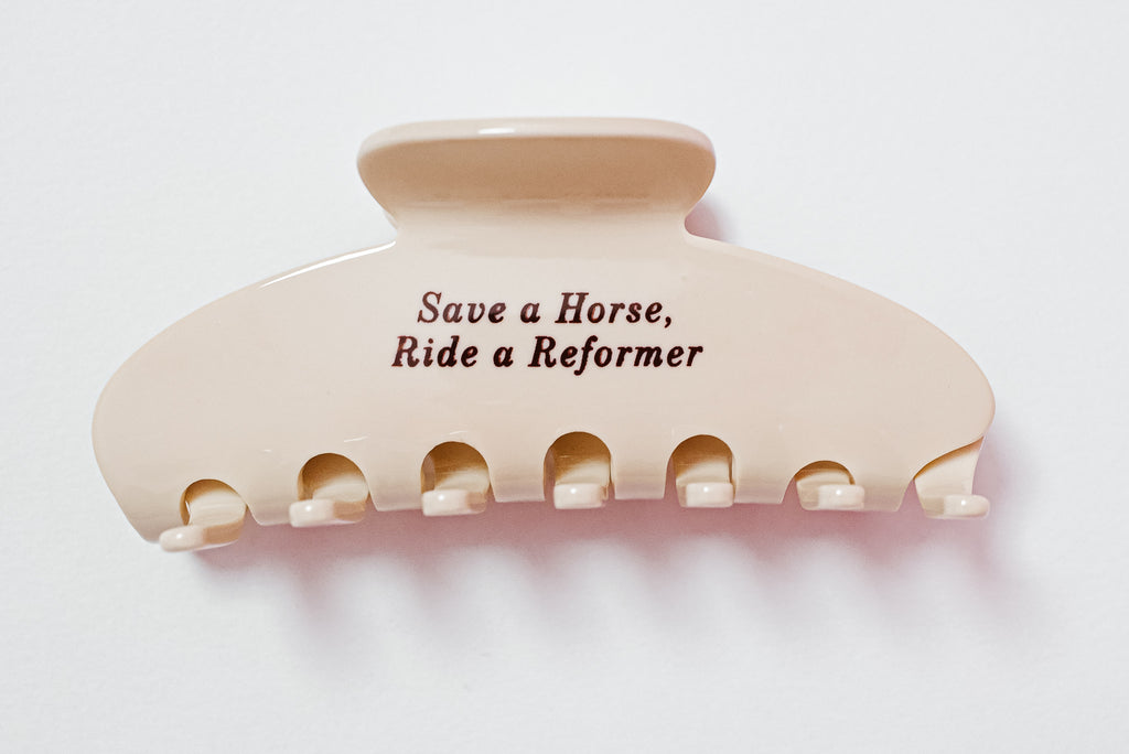 Cream hair clip with text 'Save a Horse, Ride a Reformer' on a white background