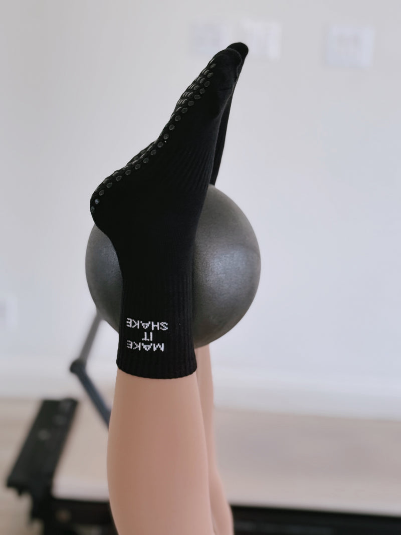 Black grip sock with text on a foot saying "make it shake" against a white background